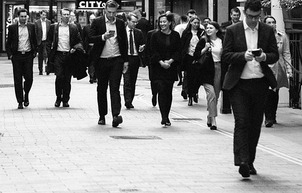 business people walking on street looking at phones