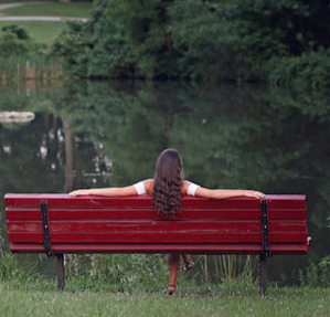 woman sitting on bench by a lake